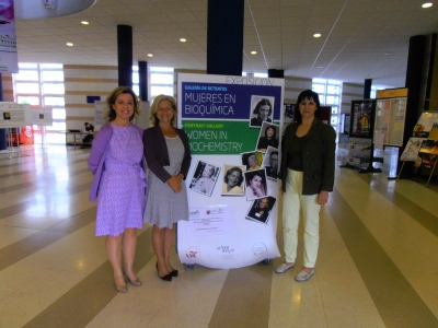 De izq. a dcha. Maria Dolores Calzada, Carmen Galán y Gloria Priego ante el cartel de la exposición.